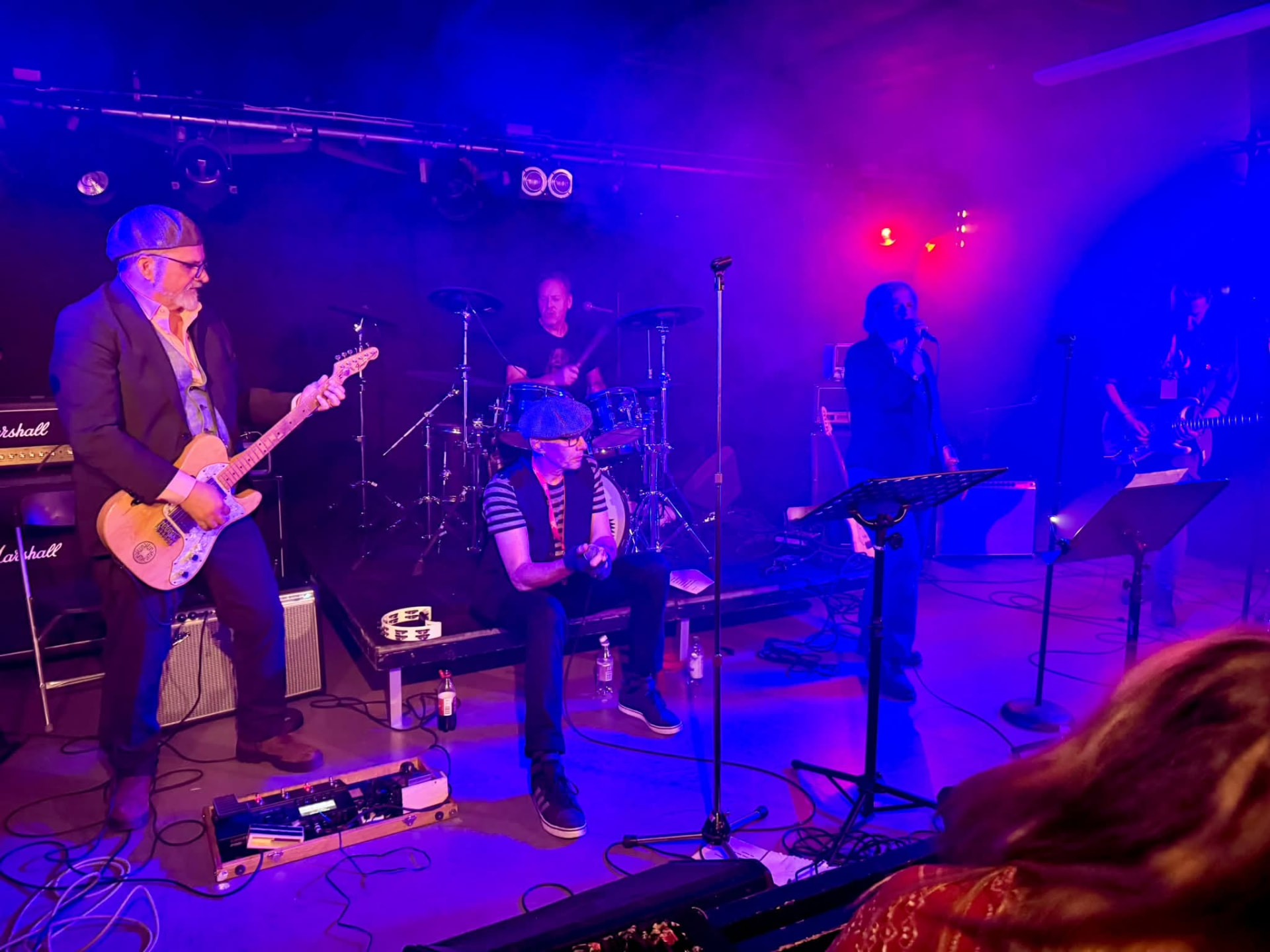 Band som spelar live på scen i blått och rödlilla scenljus