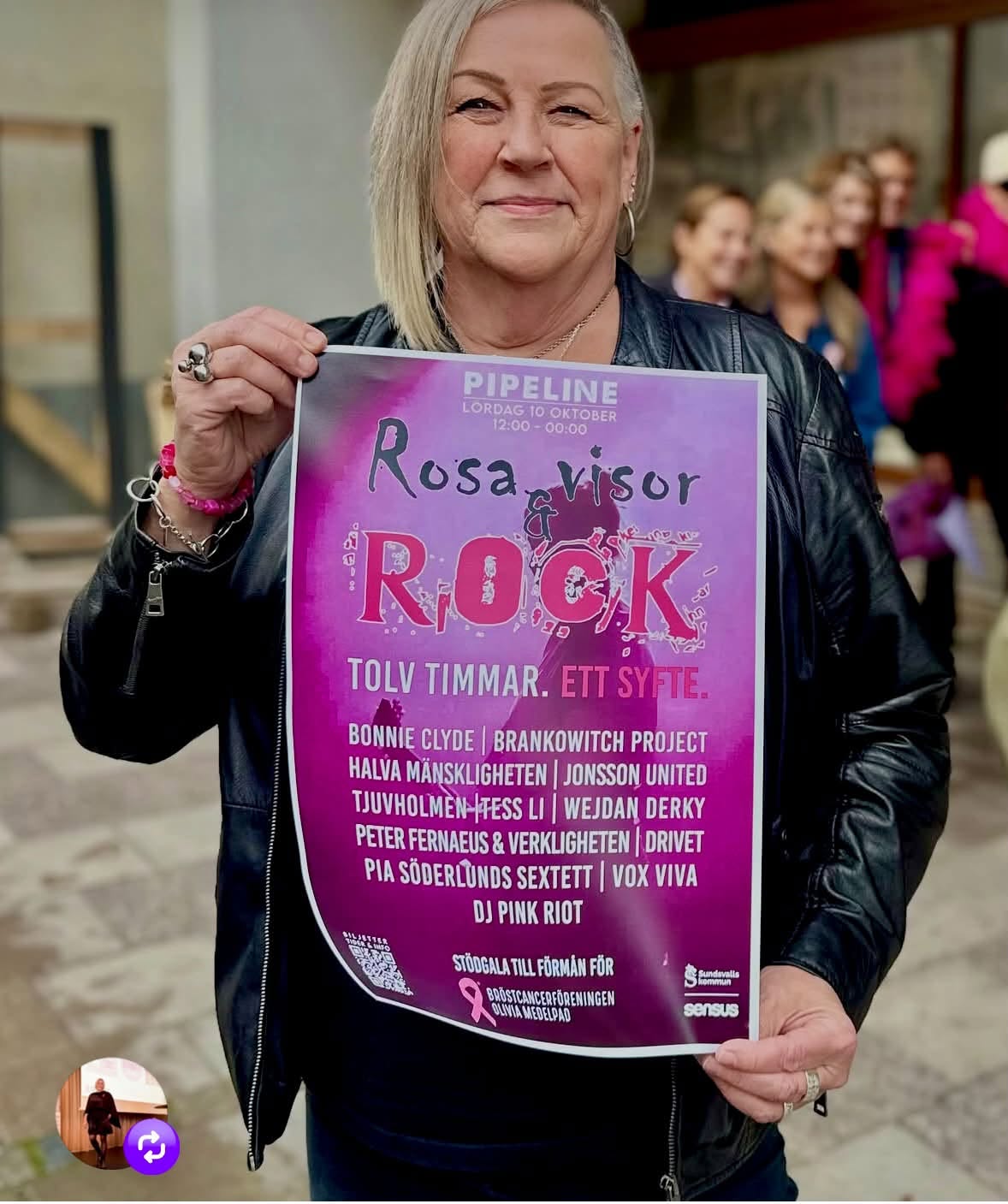 Kvinna i svart skinnjacka håller upp en rosa affisch med information om galakvällen