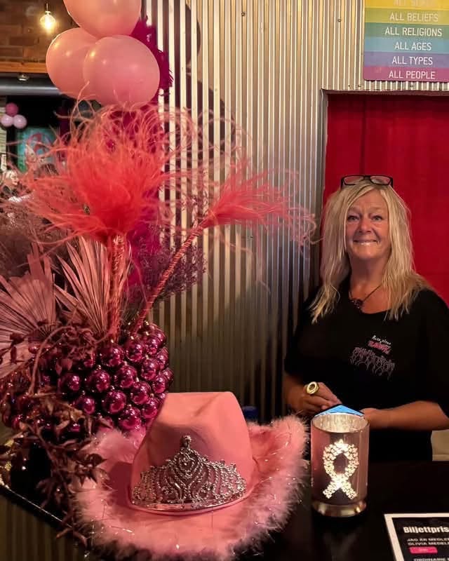 Kvinna bakom en disk vid ingången dekorerad med rosa ballonger, fjädrar, hatt med tiara och ljuslykta med rosa band